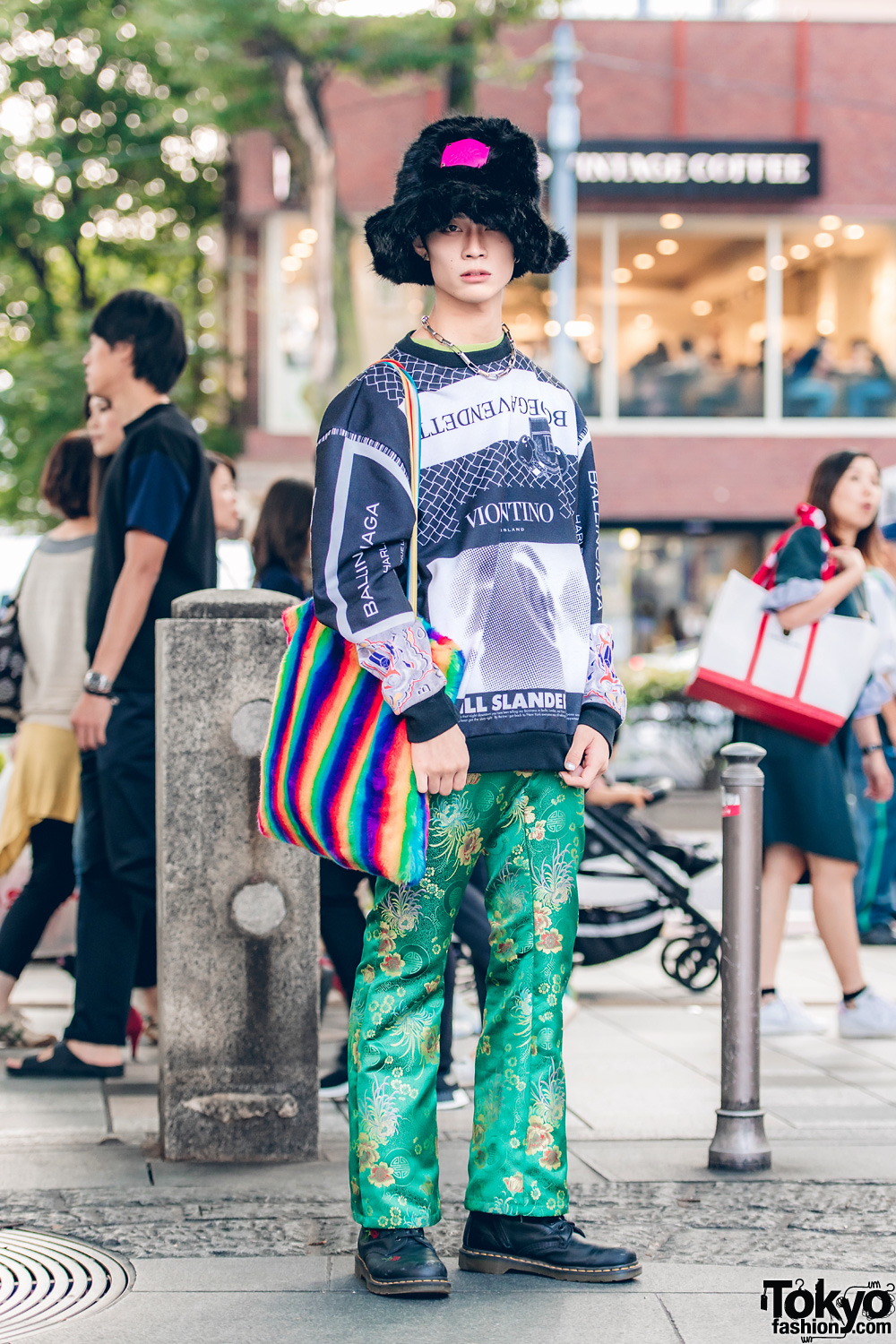 Harajuku Guy in Faux Fur Hat, Graphic Top, Floral Pants, & Rainbow Striped Bag