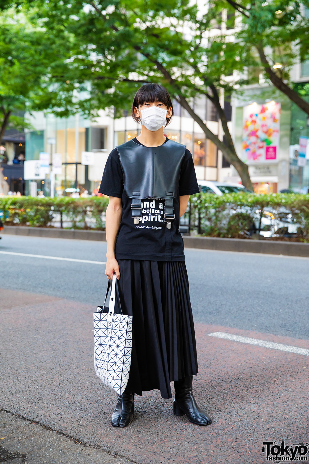 Tokyo Comme des Garcons Street Style w/ White Face Mask, Leather Half Vest, Statement Shirt, Pleated Skirt, Issey Miyake Bao Bao Bag & Maison Margiela Tabi Boots